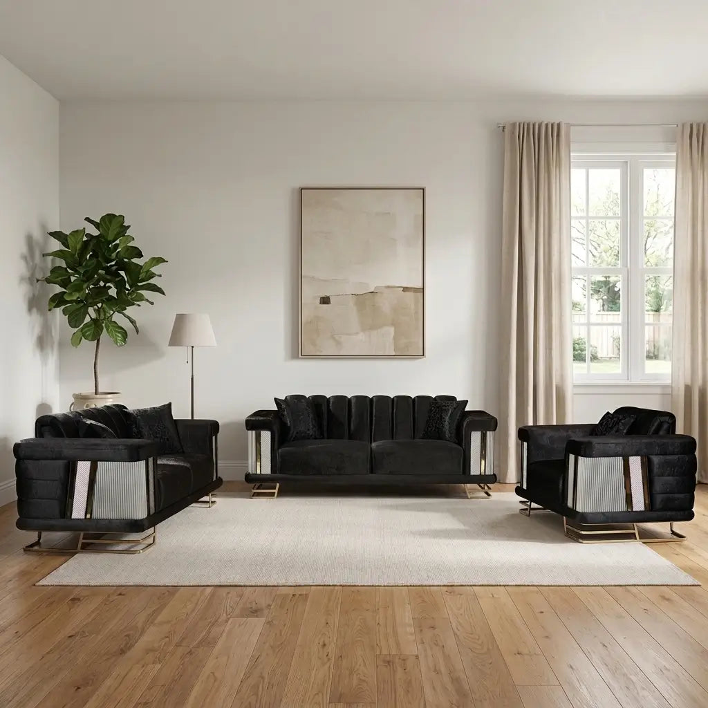 A modern living room set featuring a black velvet sofa, matching armchair, and side table with silver geometric side panels and gold legs