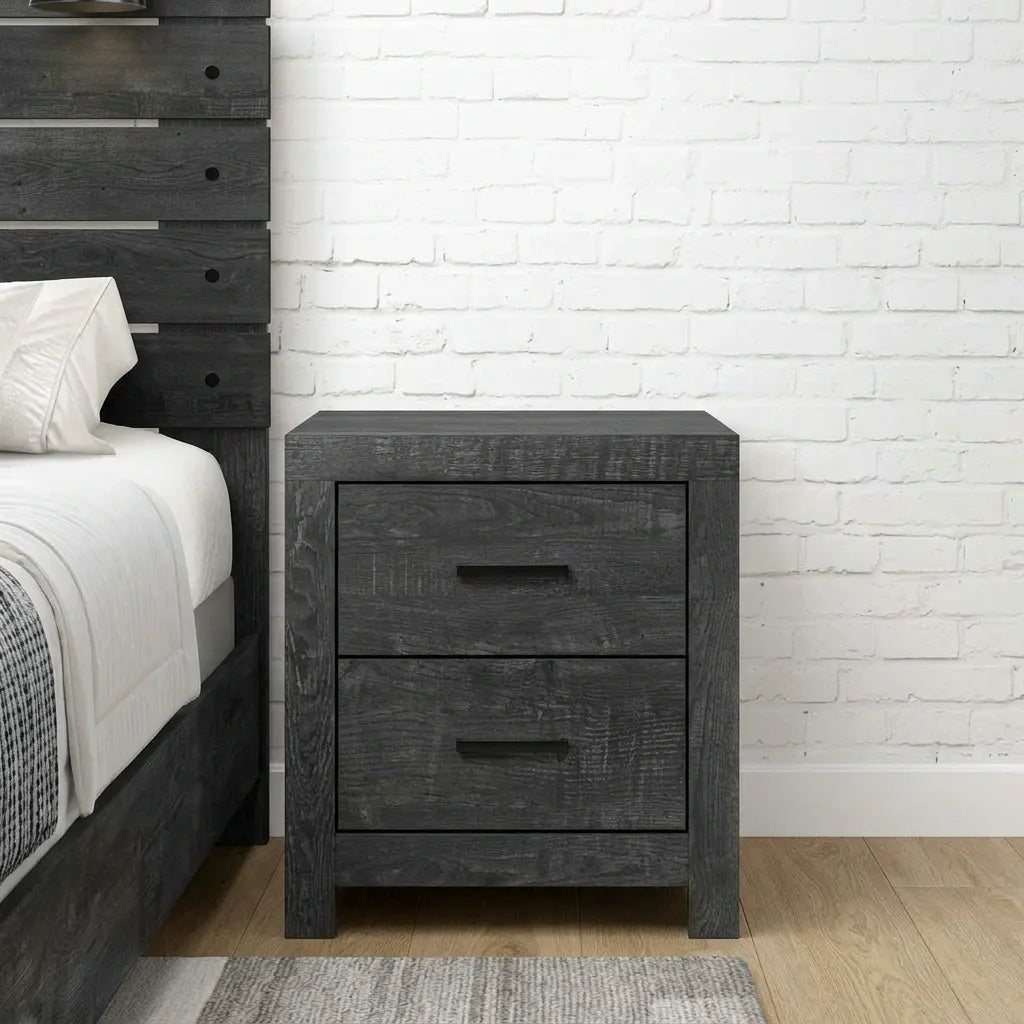 Rustic dark charcoal gray wood 2-drawer nightstand with black bar pulls placed next to a wooden bed frame.