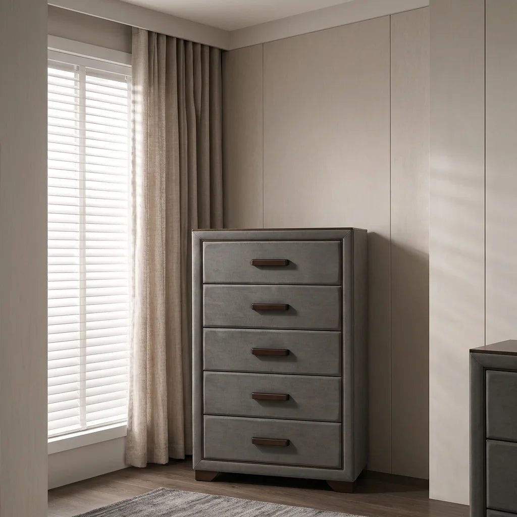 Modern grey upholstered 5-drawer tall chest with dark wood bar pulls near sunlit window